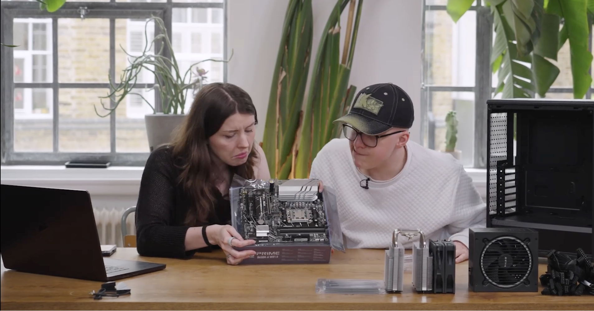Two tech journalists looking confused at a motherboard