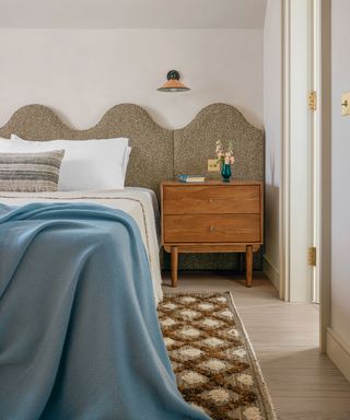 Guest bedroom with white walls, blue bedding and curved headboard