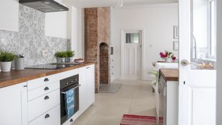 white galley kitchen with open door and view of brick fireplace