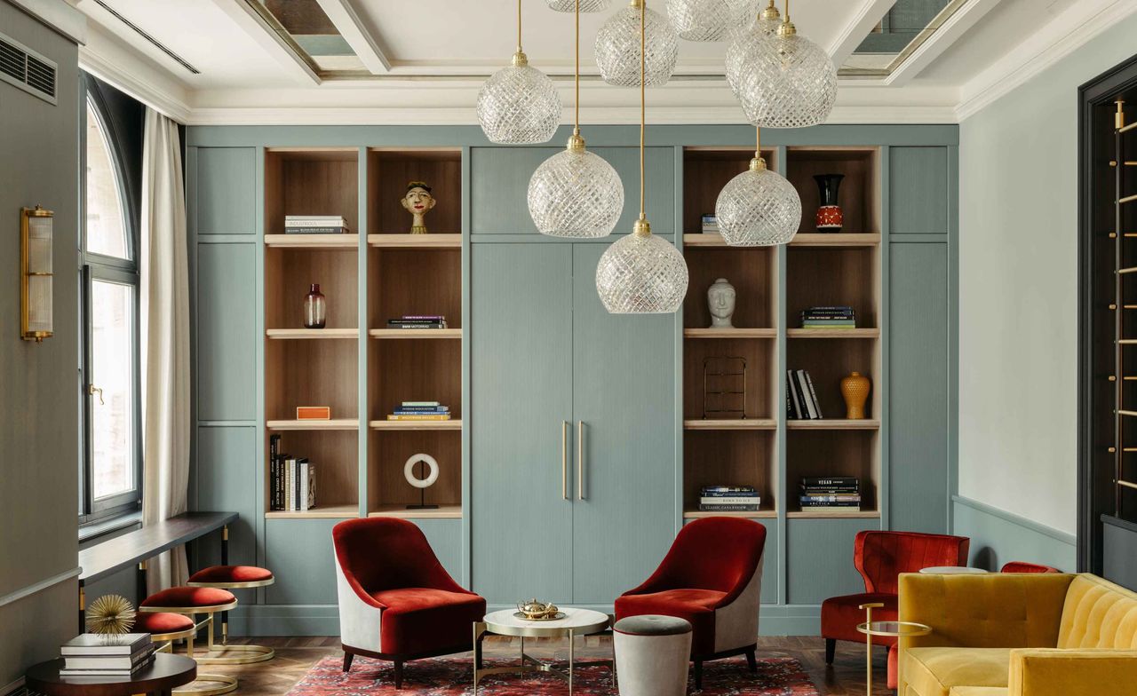 Ameron Boutique hotel lounge with teal wall units, burnt orange tub chairs, mustard sofa and hanging glass lamps