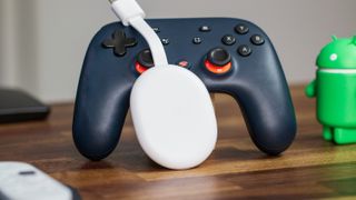Chromecast with Google TV HD leaning on Stadia controller