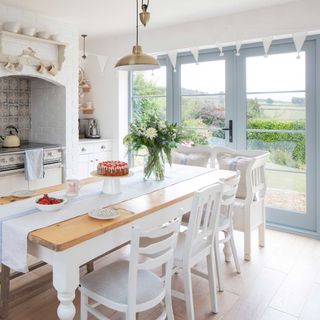 white cottage kitchen with farmhouse table, range and french doors to garden