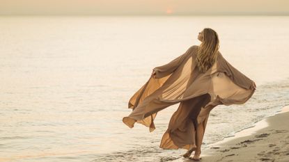 Summer perfumes: a woman stands under a yellow sun shade in a meadow