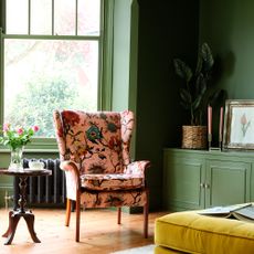 Green-painted living room with pink patterned armchair