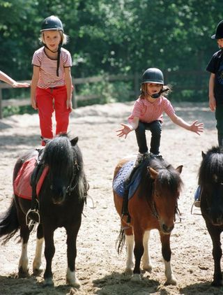 Children standing on horse back