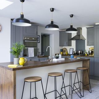 kitchen area with ceiling lamp and wooden worktop with stools