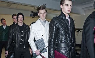 Models in a line for a fashion show wearing various coats, mainly leather