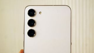 The Samsung Galaxy S23 Plus in white, shown from the back with its three-camera array