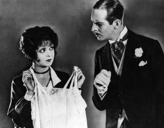 Clara Bow holds up some underwear, watched suspiciously by William Austin, in a scene from the film, 'It'.