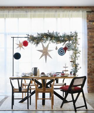A DIY handmade Christmas feature in dining room with dining set with clothes rail, paper honeycomb decorations and frosted fir garlan foliage