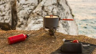 Camping stove and fuel bottle on cliff