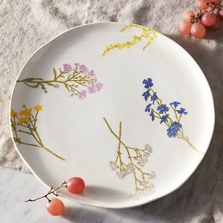 A painted plate on a tablecloth with grapes