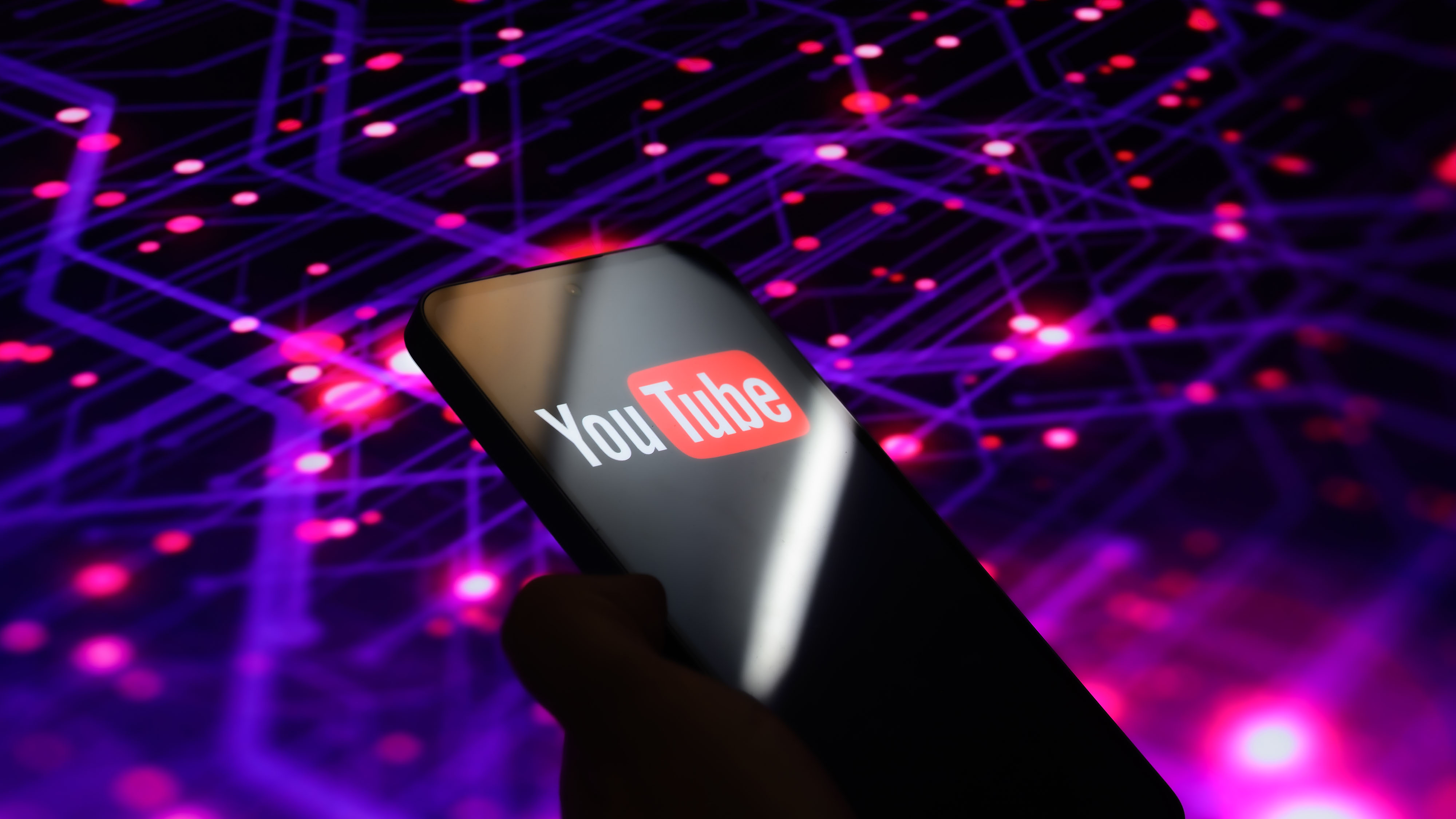 A person holds a phone with the YouTube logo and a tech background