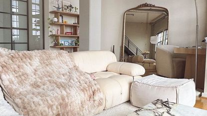 A white couch and mirror in a neutral living room