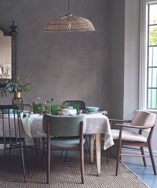 Upholstered dining chairs and dining table with linen tablecloth on jute rug. Seasonal decorating ideas.