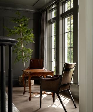 A green living room with an antique wooden table and two leather armchairs
