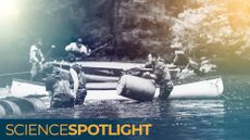 men standing in a river with canoes lift barrels