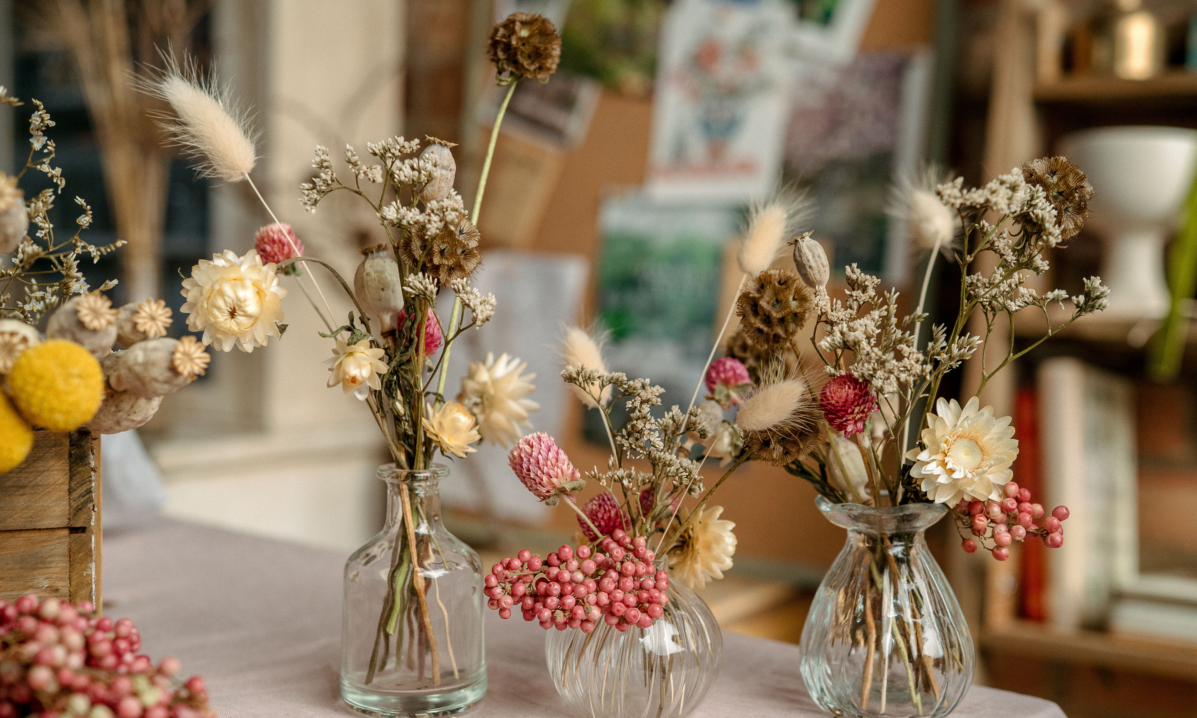 Three clear glass bud vases with dried flower design in them