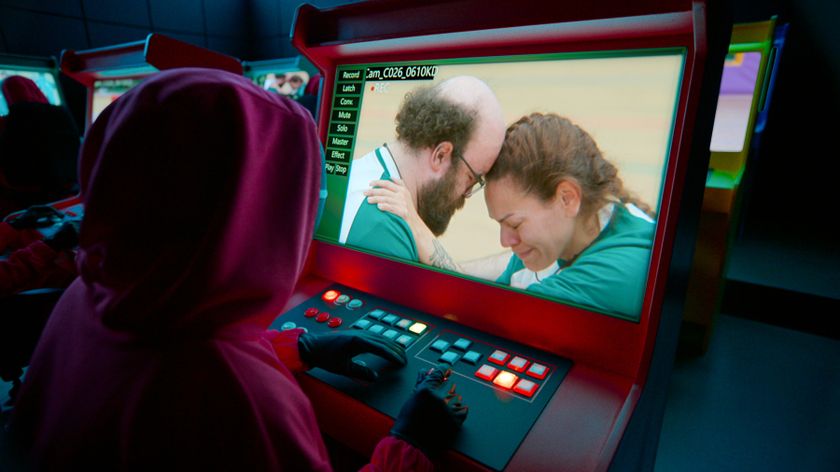 A &quot;Squid Game&quot; guard watches two contestants on a monitor in a still from Netflix&#039;s &quot;Squid Game: The Challenge&quot; season 2
