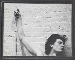 Self-portrait of Robert Mapplethorpe with trip cable in hand, 1974