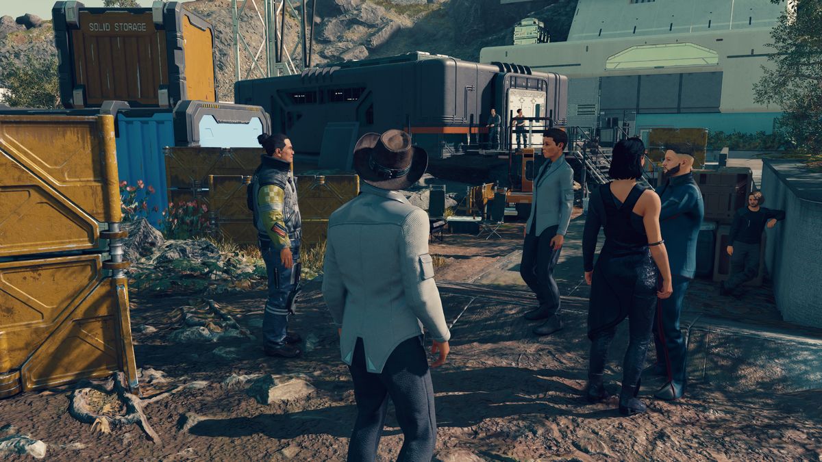 Starfield — a gathering of people at an outpost, surrounded by storage crates and concrete barriers.