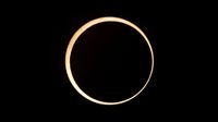 view of annular solar eclipse with moon in the enter obscuring a majority of the sun's disk, leaving a ring of fire around the outside.