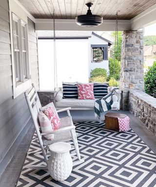 Grey and pink front porch ideas by Alieta Casey using geometric rug, porch swing and assorted cushions