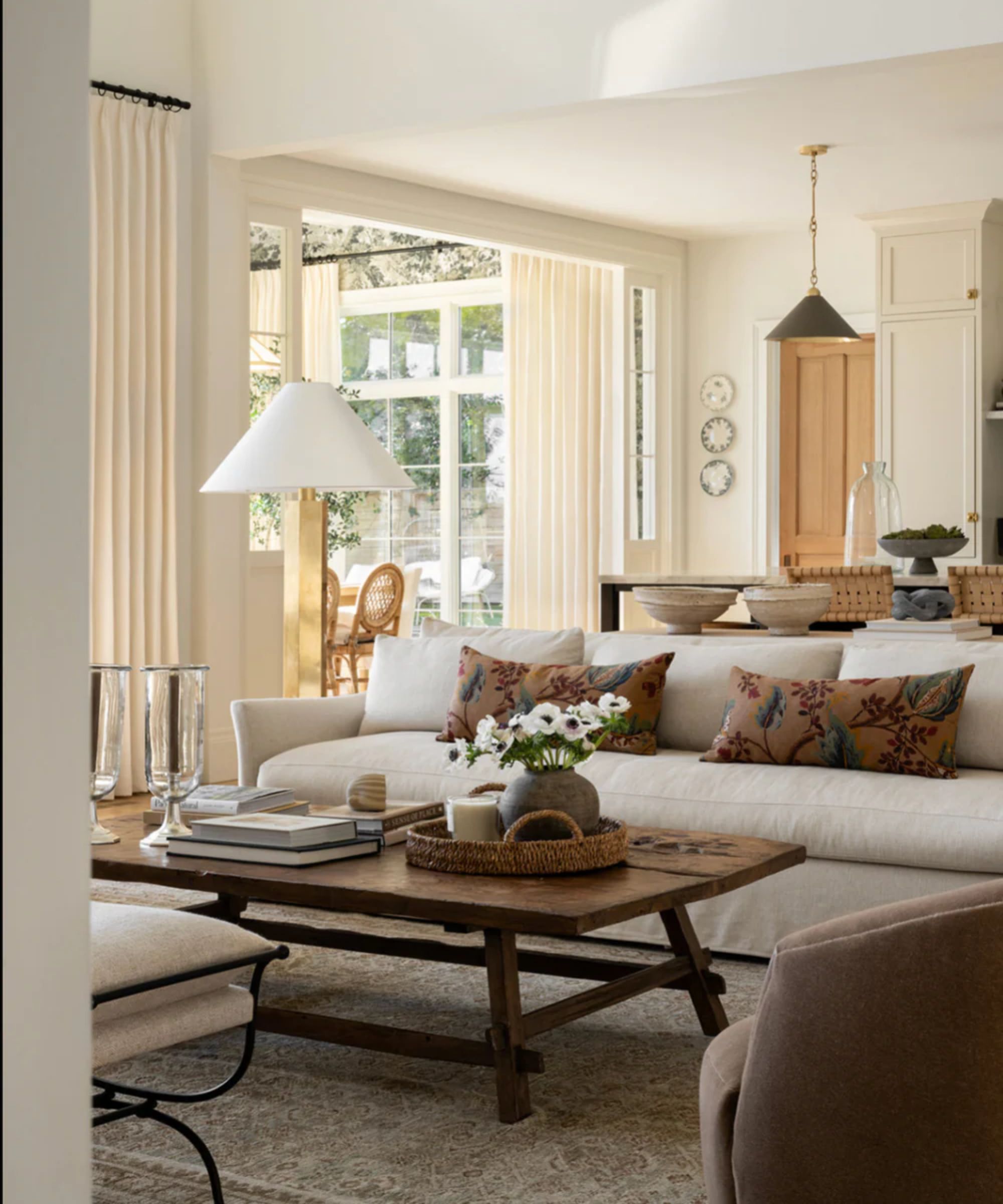 neutral living room open pln kitchen with neutral couch, wooden coffee table, and earthy floral cushions
