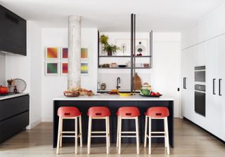 modern kitchen with black island and a repetition of four red bar stools