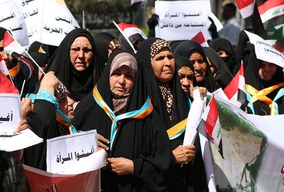 Iraqi women hold signs saying "Help women who are abused by DAESH (ISIS)" during September 2014 protest