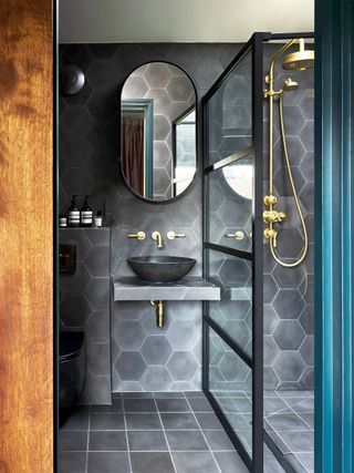 shower room with dark gray hexagonal tiles and square floor tiles and brass fittings and bowl sink
