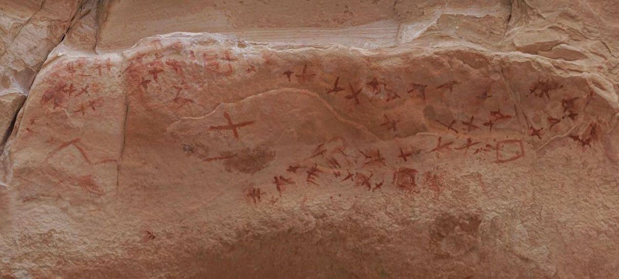 Тамносмеђи цртежи се виде на доњој страни надвишења црвенкасто браон стене. 