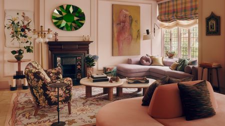 Pale pink living room with lilac corner sofa, two nesting coffee tables, floral rug, abstract artwork and green stained glass artwork