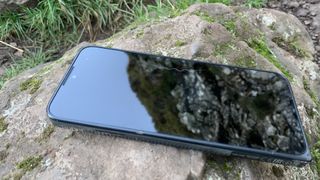 A smartphone lying on a rock with a dog hair on the screen