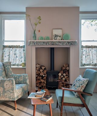 pink living room with wood burner and floral upholstered chair and curtains