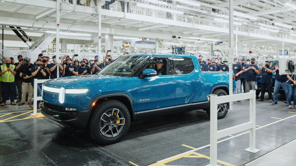 Electric truck rolling off a production line in a factory surrounded by workers