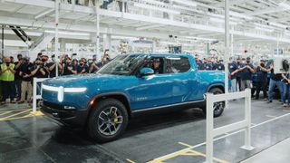 Electric truck rolling off a production line in a factory surrounded by workers