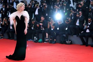 Cate Blanchett schaut ihr auf dem roten Teppich der Filmfestspiele von Venedig in einem schwarzen Kleid über die Schulter