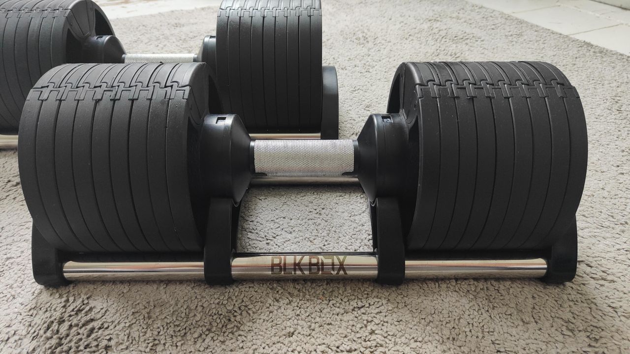 Closeup of the BLK BOX Adjustable Dumbbell on a carpeted floor