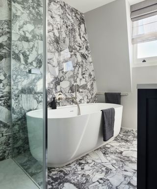 white bathroom with marble floor and wall and freestanding tub