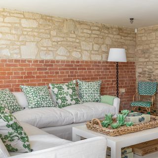 Living room with exposed brick work, white sofa and patterned cushions