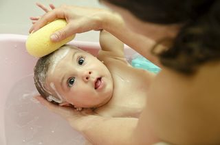 A woman gives a baby a bath