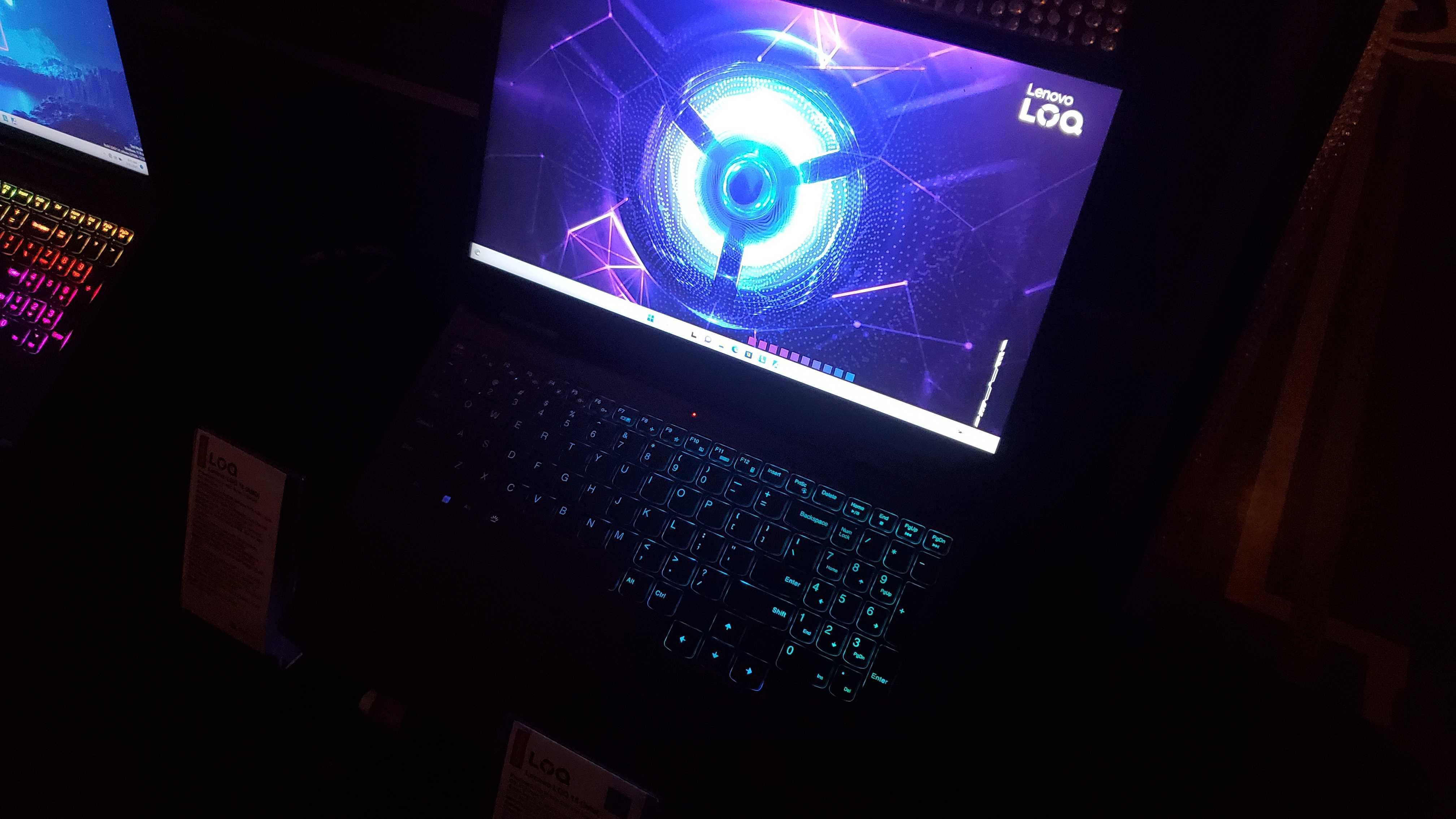 dark laptop with RGB lighting, display showing logo