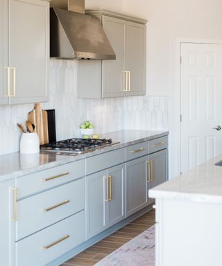Small clutter-free kitchen with light blue cabinets and gray marble counters