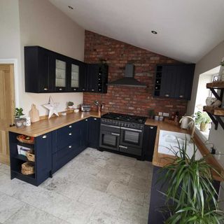 kitchen with black cabinets wooden counter red brick and white wall and grey flooring