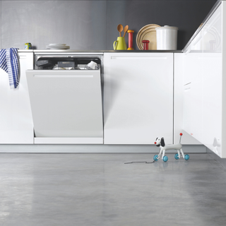 White fitted kitchen units grey polished concrete floor toy dog open dishwasher door