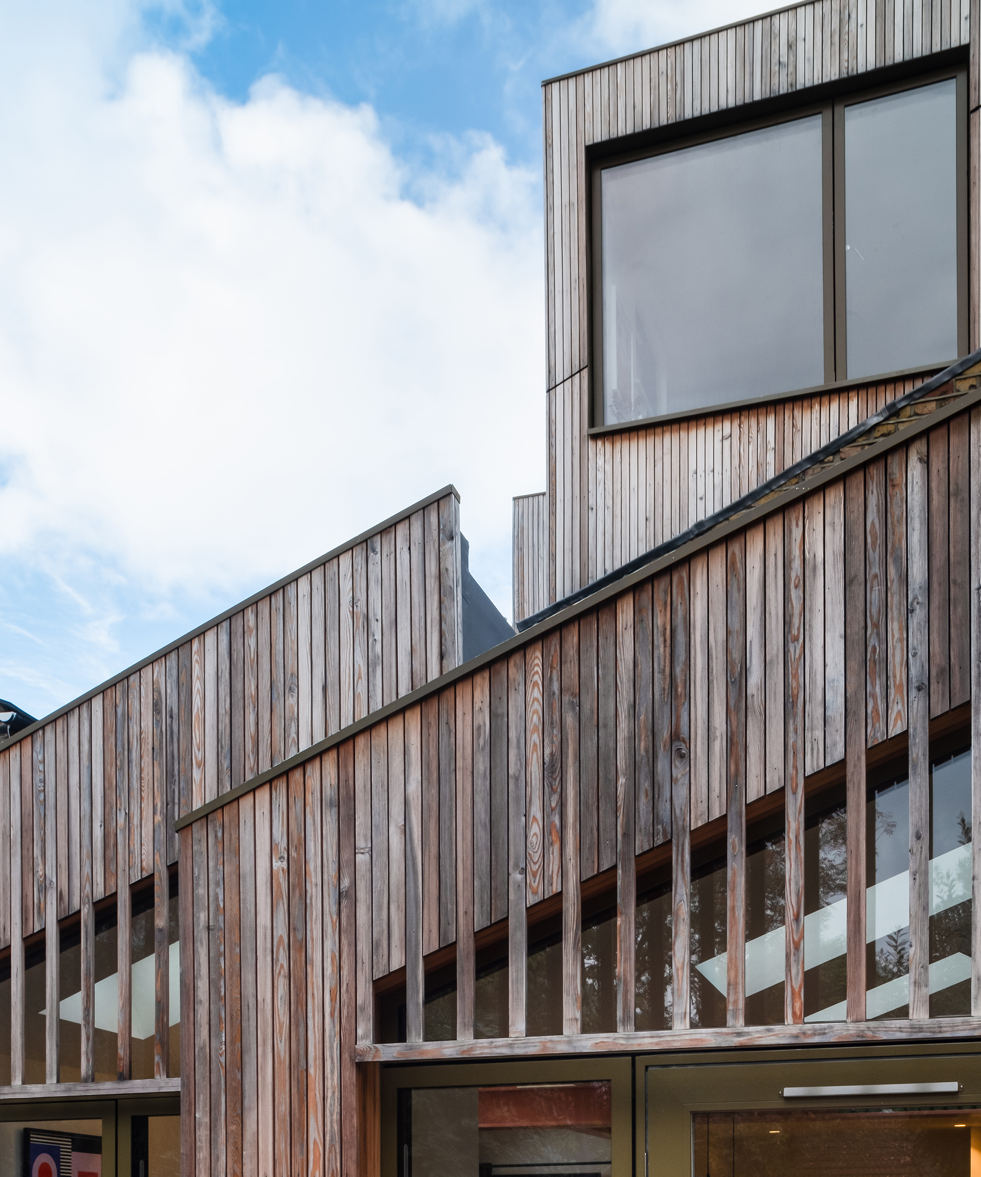 An angled shot of the exterior of a timber clad house extension. The he extension comprises of a ground floor as well as a loft