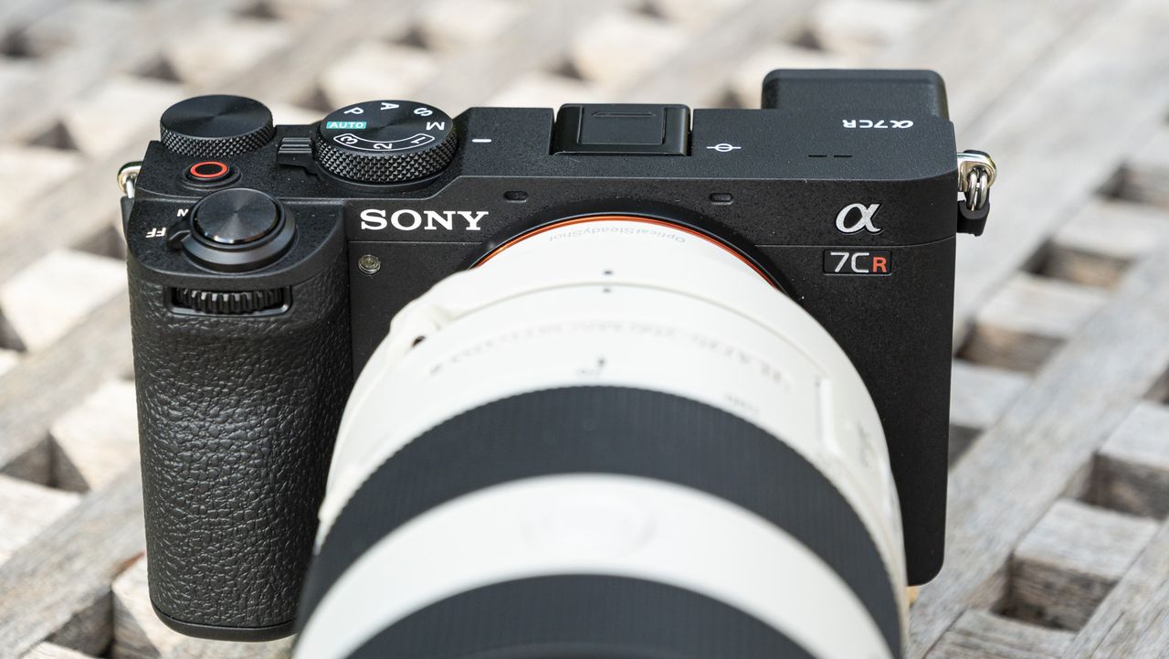 Sony A7C R mirrorless camera outside on a wooden table with FE 70-200mm F4 II lens attached
