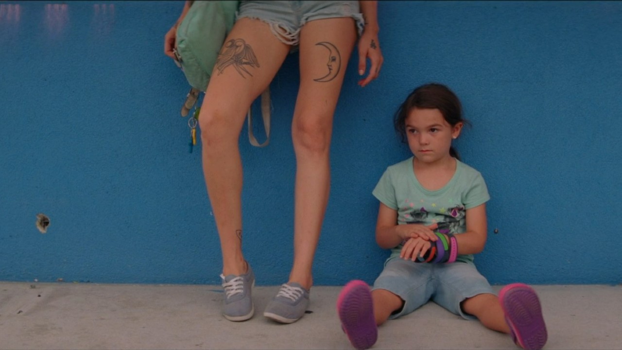 Brooklynn Prince sitting with Bria Vinaite standing by her in The Florida Project.