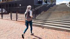 Woman walking away from the camera towards steps wearing workout clothes and trainers, representing the benefits of walking for lower back pain